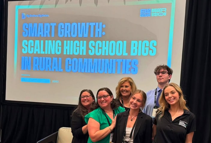 BBBSWNC staff members standing in front of a screen about High School Bigs